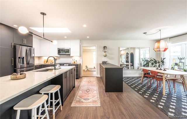 995 Chase St, Lakewood, CO 80214 - kitchen with stainless steel appliances, wood finished floors, decorative light fixtures, a kitchen breakfast bar, and light countertops