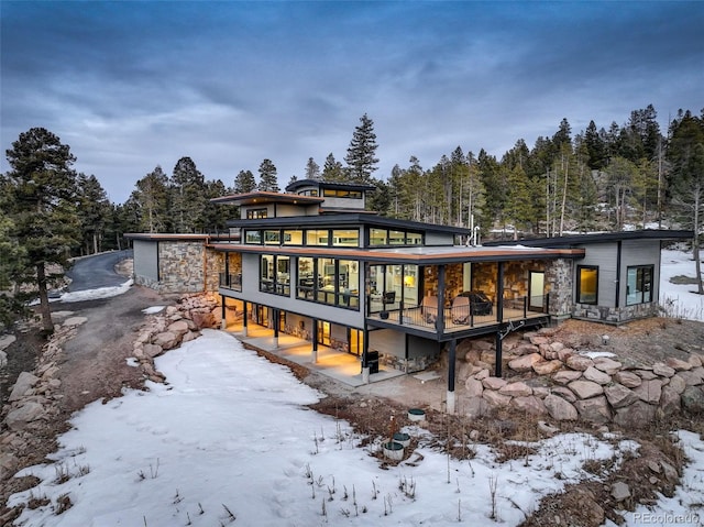 snow covered property with stone siding