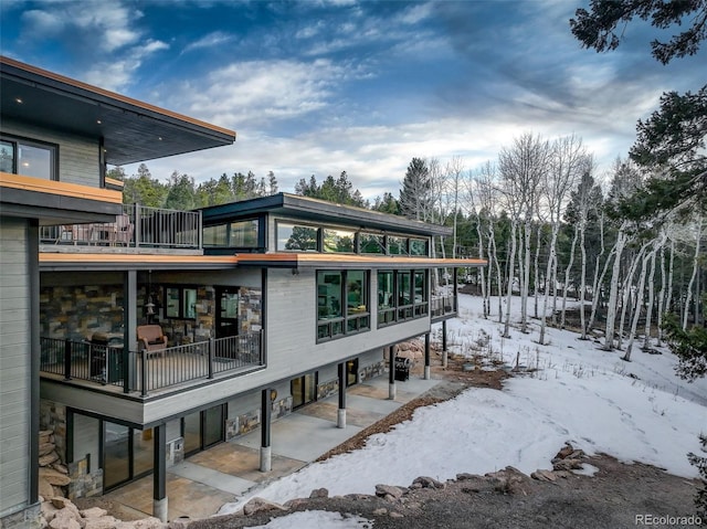 exterior space featuring stone siding and a balcony