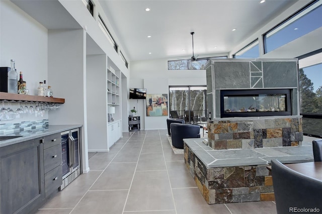 living room featuring light tile patterned floors, wine cooler, built in shelves, recessed lighting, and a dry bar