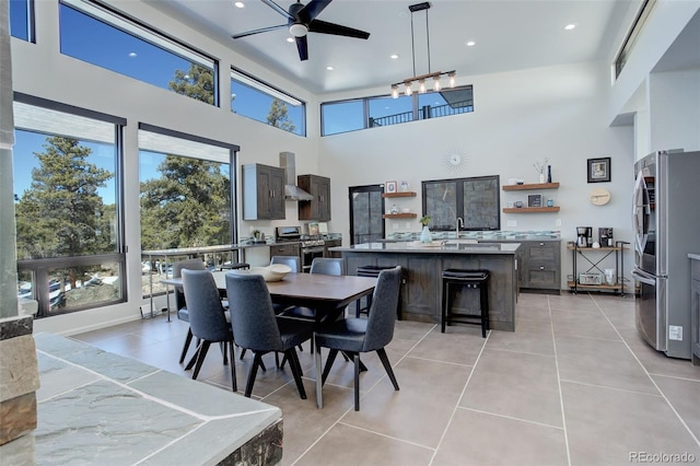 dining area featuring recessed lighting, light tile patterned flooring, ceiling fan, and a towering ceiling