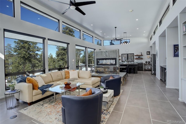 living room with light tile patterned floors, ceiling fan, a high ceiling, and recessed lighting