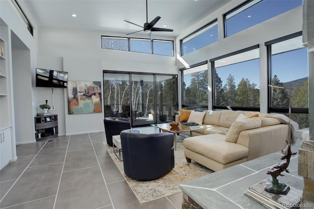 tiled living area with a ceiling fan, recessed lighting, a towering ceiling, and built in shelves