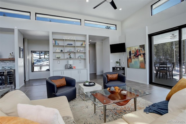 living area featuring recessed lighting, beverage cooler, a ceiling fan, a towering ceiling, and tile patterned floors