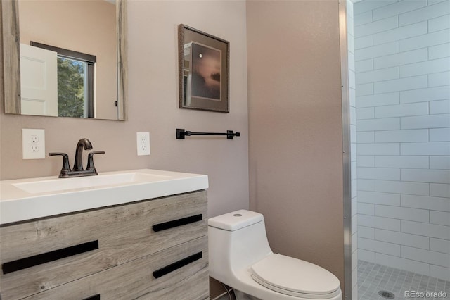 full bathroom with a tile shower, vanity, and toilet