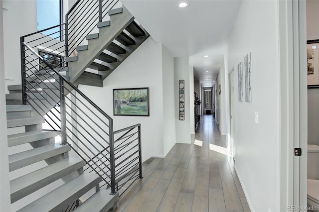 stairs featuring baseboards, wood finished floors, and recessed lighting