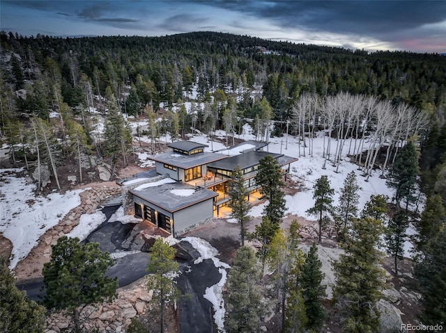 snowy aerial view featuring a forest view