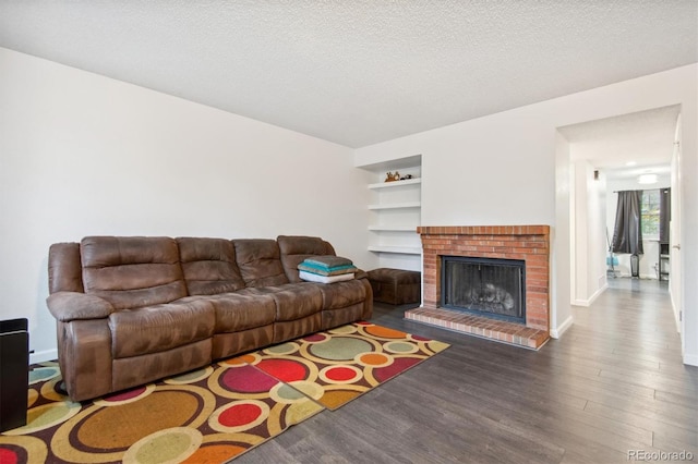 living room with built in shelves, hardwood / wood-style floors, a fireplace, and a textured ceiling