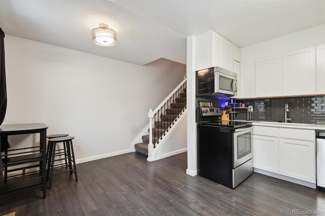 kitchen featuring stainless steel appliances, a textured ceiling, dark hardwood / wood-style floors, decorative backsplash, and white cabinets