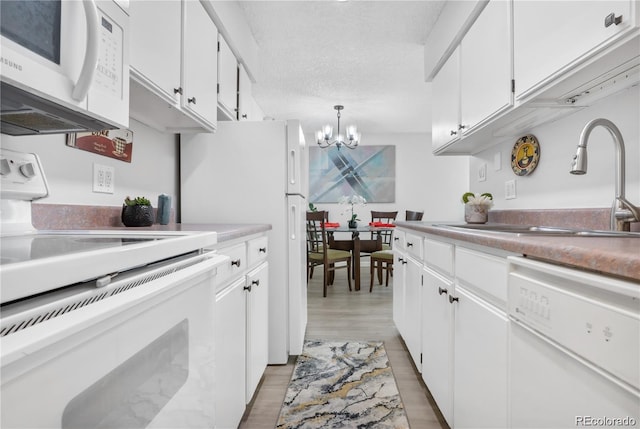 kitchen with white cabinets, white appliances, a chandelier, and sink