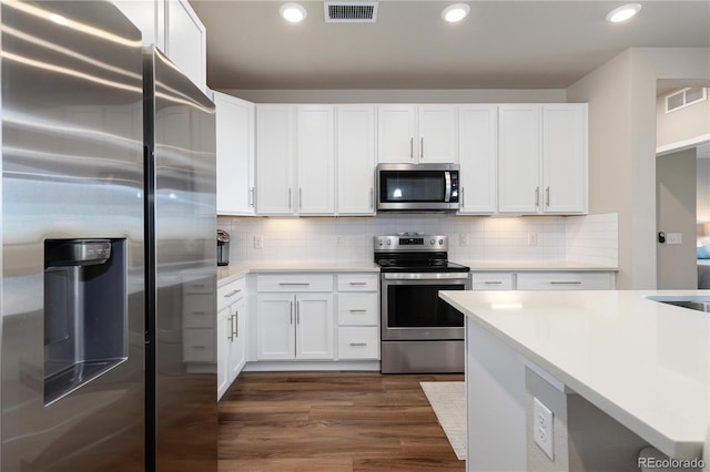kitchen featuring stainless steel appliances, dark wood finished floors, light countertops, white cabinetry, and backsplash