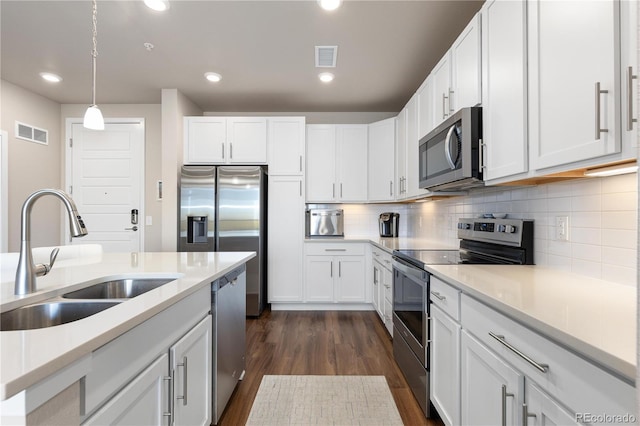 kitchen with stainless steel appliances, a sink, dark wood-style flooring, white cabinetry, and light countertops