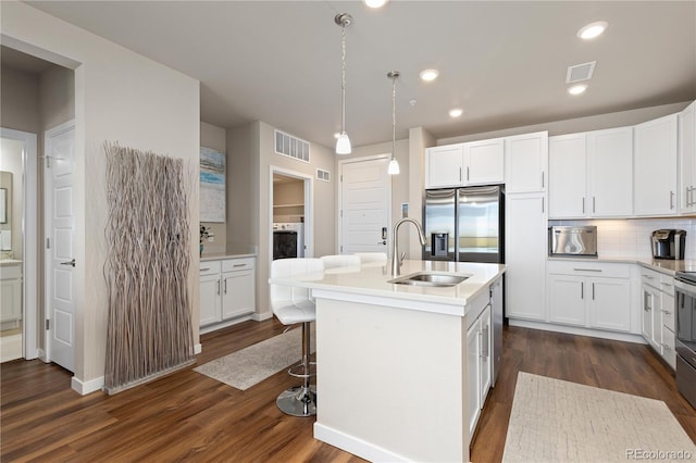 kitchen featuring a sink, stainless steel fridge with ice dispenser, dark wood finished floors, tasteful backsplash, and white cabinetry
