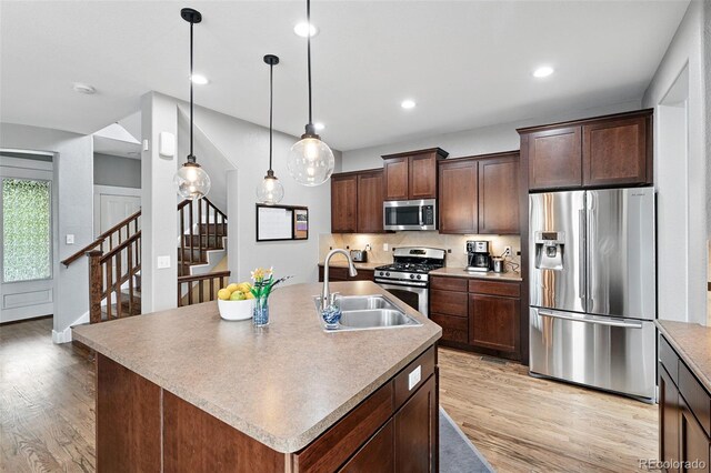 3644 Wabash St, Denver, CO 80238 - kitchen with appliances with stainless steel finishes, a sink, light wood-style floors, an island with sink, and recessed lighting