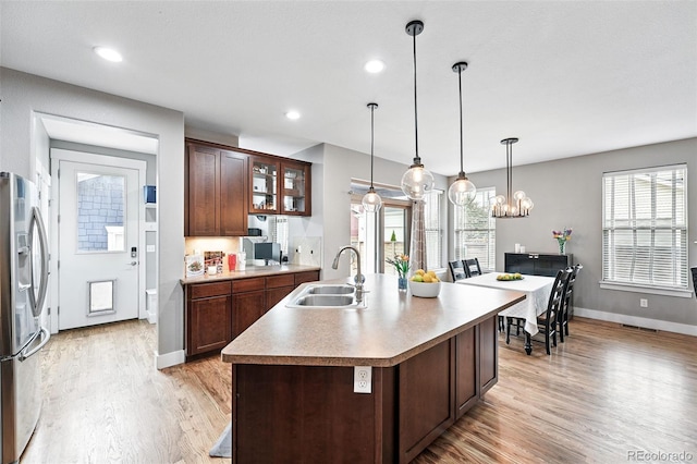 3644 Wabash St, Denver, CO 80238 - kitchen featuring stainless steel refrigerator with ice dispenser, a sink, light wood-style floors, an island with sink, and glass insert cabinets