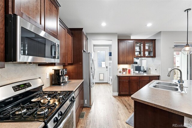 3644 Wabash St, Denver, CO 80238 - kitchen featuring stainless steel appliances, a sink, light wood-style flooring, decorative light fixtures, and backsplash