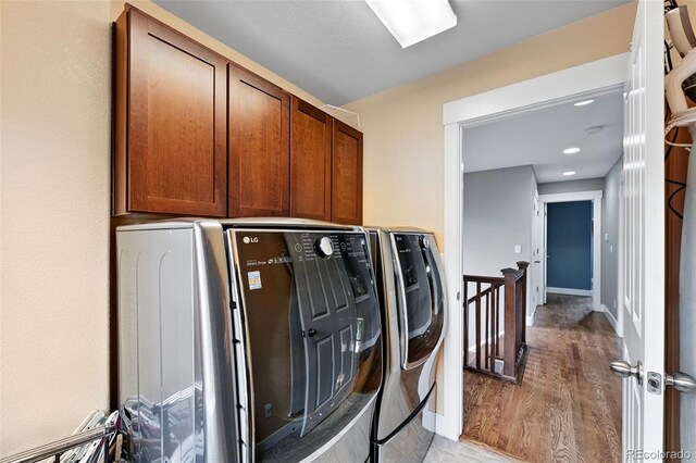 3644 Wabash St, Denver, CO 80238 - laundry area featuring washing machine and clothes dryer, cabinet space, and light wood-style flooring