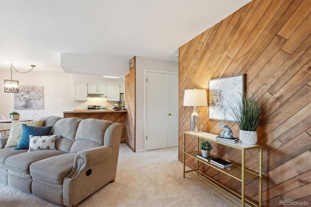 living room featuring wood walls, a chandelier, and light colored carpet