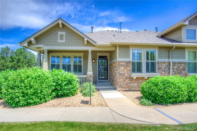 8594 W Quarto Ave, Littleton, CO 80128 - view of front of property with a shingled roof, covered porch, and stone siding