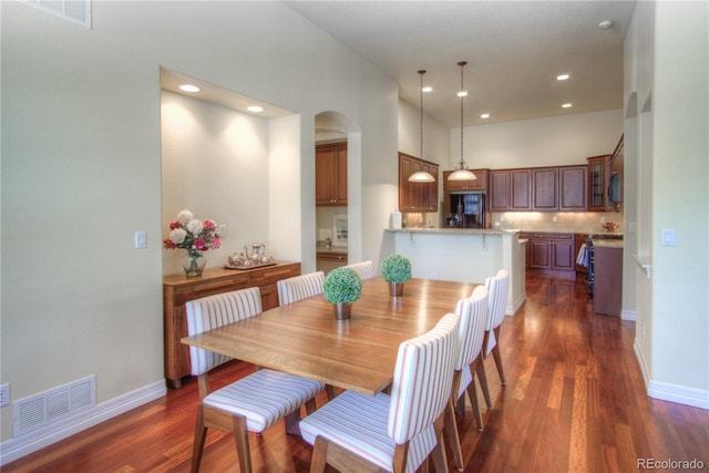 8594 W Quarto Ave, Littleton, CO 80128 - dining area featuring dark wood finished floors, arched walkways, a high ceiling, and recessed lighting