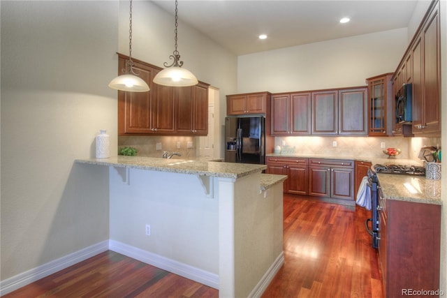 8594 W Quarto Ave, Littleton, CO 80128 - kitchen with black appliances, a peninsula, a kitchen bar, dark wood-style floors, and recessed lighting