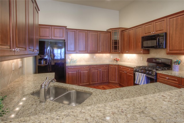 8594 W Quarto Ave, Littleton, CO 80128 - kitchen with black appliances, light stone countertops, decorative backsplash, and glass insert cabinets
