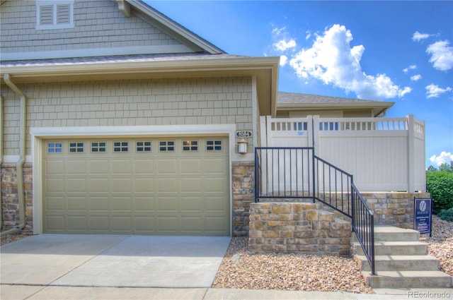 8594 W Quarto Ave, Littleton, CO 80128 - view of front of house featuring stone siding, driveway, and roof with shingles