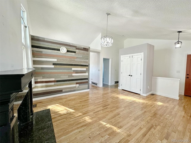 unfurnished living room with a chandelier, light wood-type flooring, and high vaulted ceiling