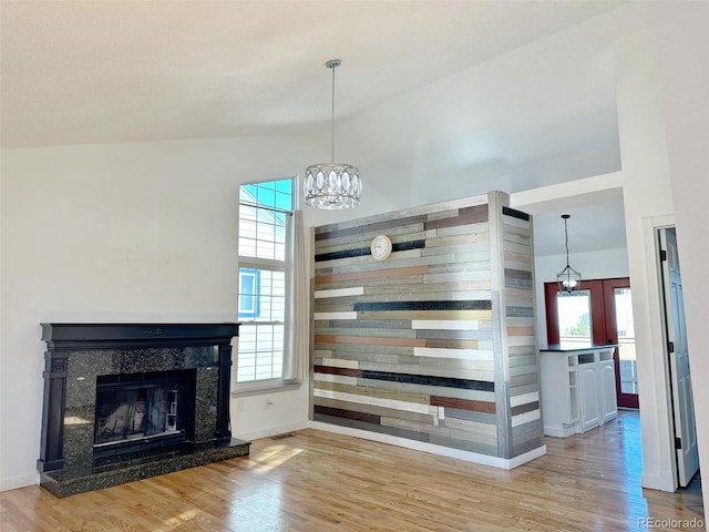 unfurnished living room featuring a high end fireplace, wood-type flooring, and high vaulted ceiling