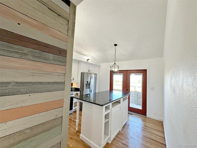 kitchen featuring a center island, lofted ceiling, french doors, white cabinets, and stainless steel fridge