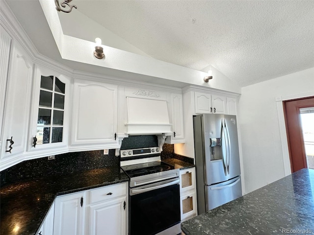 kitchen with custom exhaust hood, lofted ceiling, a textured ceiling, white cabinetry, and stainless steel appliances