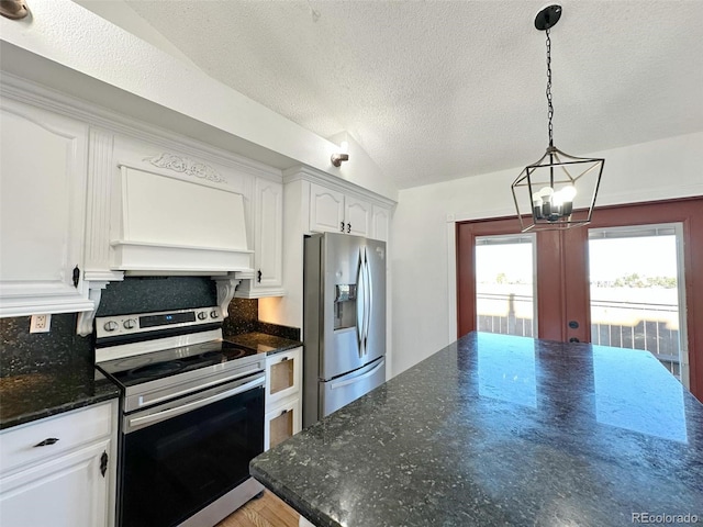 kitchen featuring stainless steel appliances, premium range hood, backsplash, dark stone countertops, and white cabinets