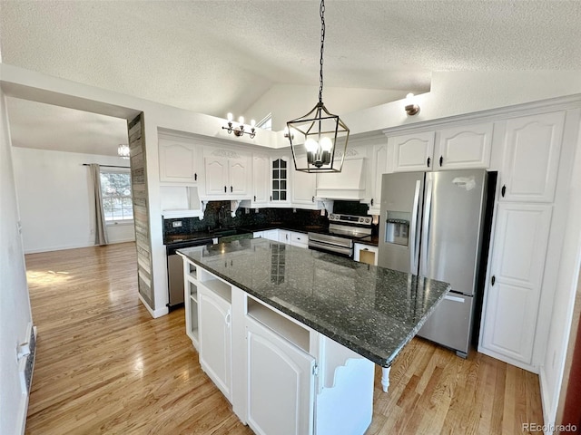 kitchen featuring lofted ceiling, light wood-type flooring, appliances with stainless steel finishes, a kitchen island, and white cabinetry