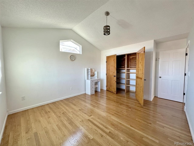 unfurnished bedroom with a textured ceiling, light hardwood / wood-style floors, and vaulted ceiling