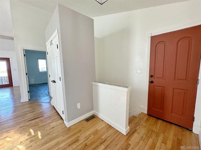 entrance foyer with a textured ceiling and light hardwood / wood-style flooring