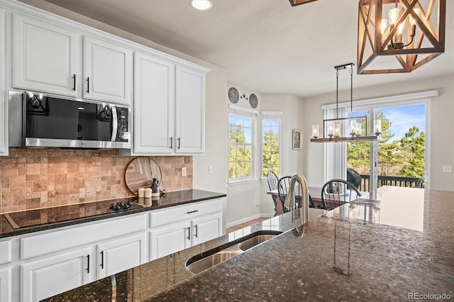 kitchen featuring stainless steel microwave, black electric cooktop, decorative backsplash, white cabinetry, and recessed lighting