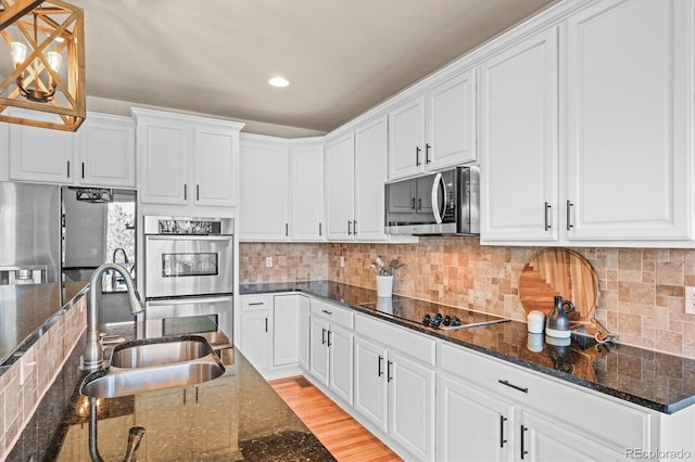 kitchen with appliances with stainless steel finishes, a sink, white cabinetry, and recessed lighting