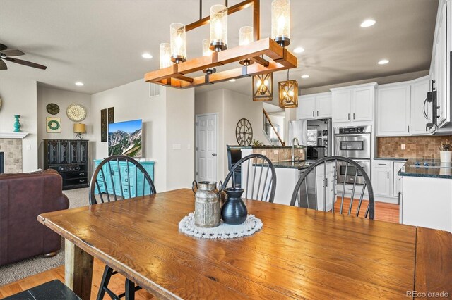 dining room with a ceiling fan, recessed lighting, a fireplace, and light wood-style flooring