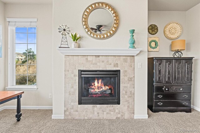 detailed view of carpet flooring, ceiling fan, a tiled fireplace, and baseboards