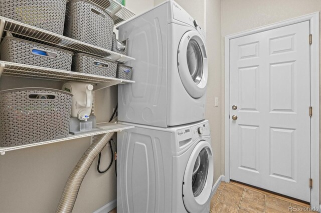 washroom featuring stacked washing machine and dryer and baseboards