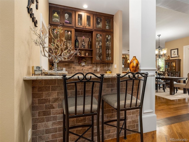 bar featuring a dry bar, wood finished floors, tasteful backsplash, and a chandelier