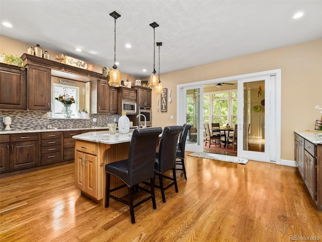 kitchen featuring a kitchen breakfast bar, light wood-style flooring, backsplash, and stainless steel appliances