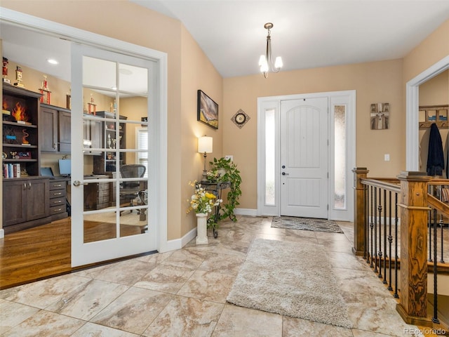 entrance foyer featuring a chandelier, a healthy amount of sunlight, french doors, and baseboards