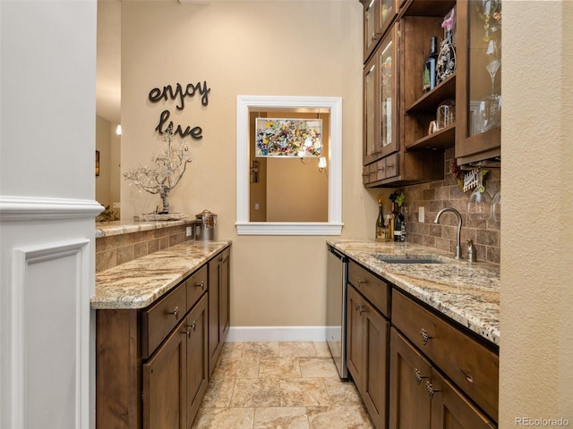 bar featuring baseboards, a sink, decorative backsplash, stone finish flooring, and stainless steel dishwasher