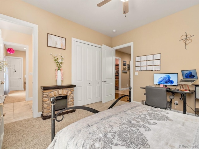 bedroom featuring a ceiling fan, a closet, carpet floors, a fireplace, and baseboards