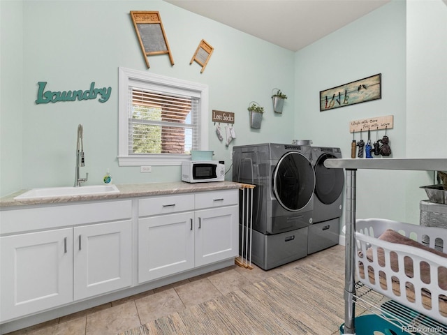 laundry room featuring cabinet space, light tile patterned floors, washing machine and dryer, and a sink