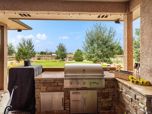 view of patio featuring grilling area, visible vents, exterior kitchen, and fence