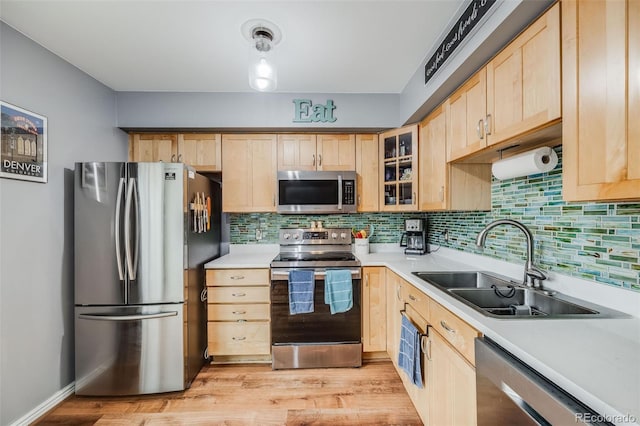 1150 Inca St Unit 43, Denver, CO 80204 - kitchen featuring appliances with stainless steel finishes, light brown cabinetry, a sink, backsplash, and glass insert cabinets