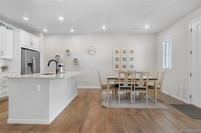 kitchen featuring light wood-style flooring, light countertops, a sink, and stainless steel fridge with ice dispenser