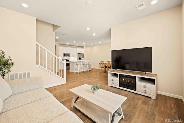 living room featuring stairs, light wood-style flooring, and recessed lighting